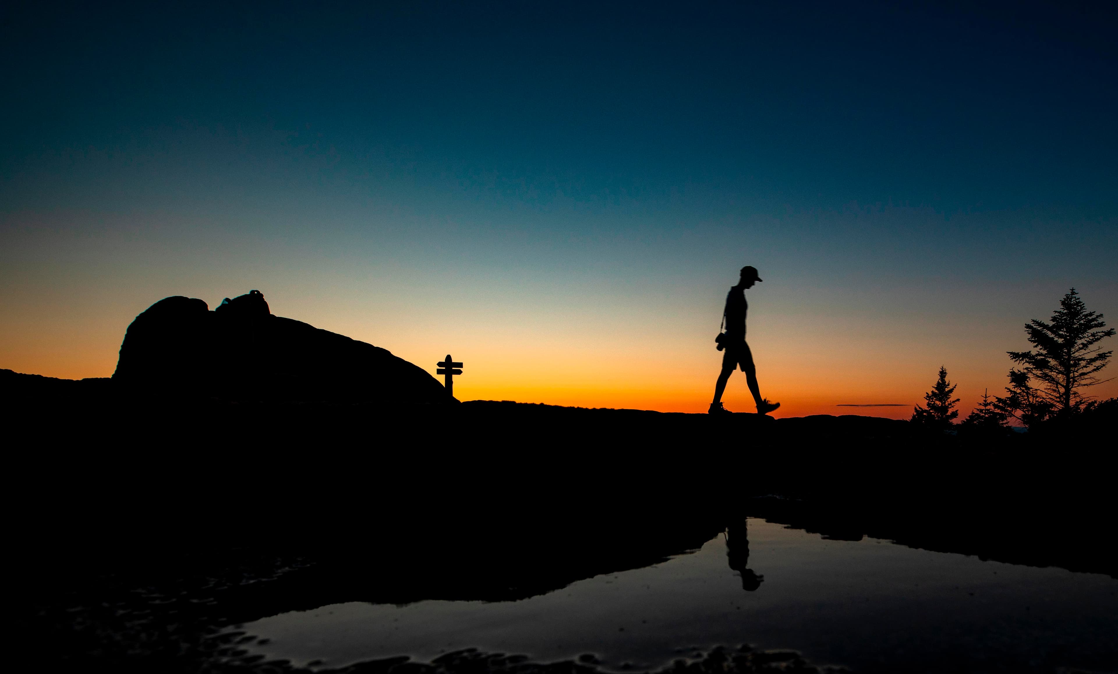 Silhouette of a hiker walking along a ridgeline at sunset